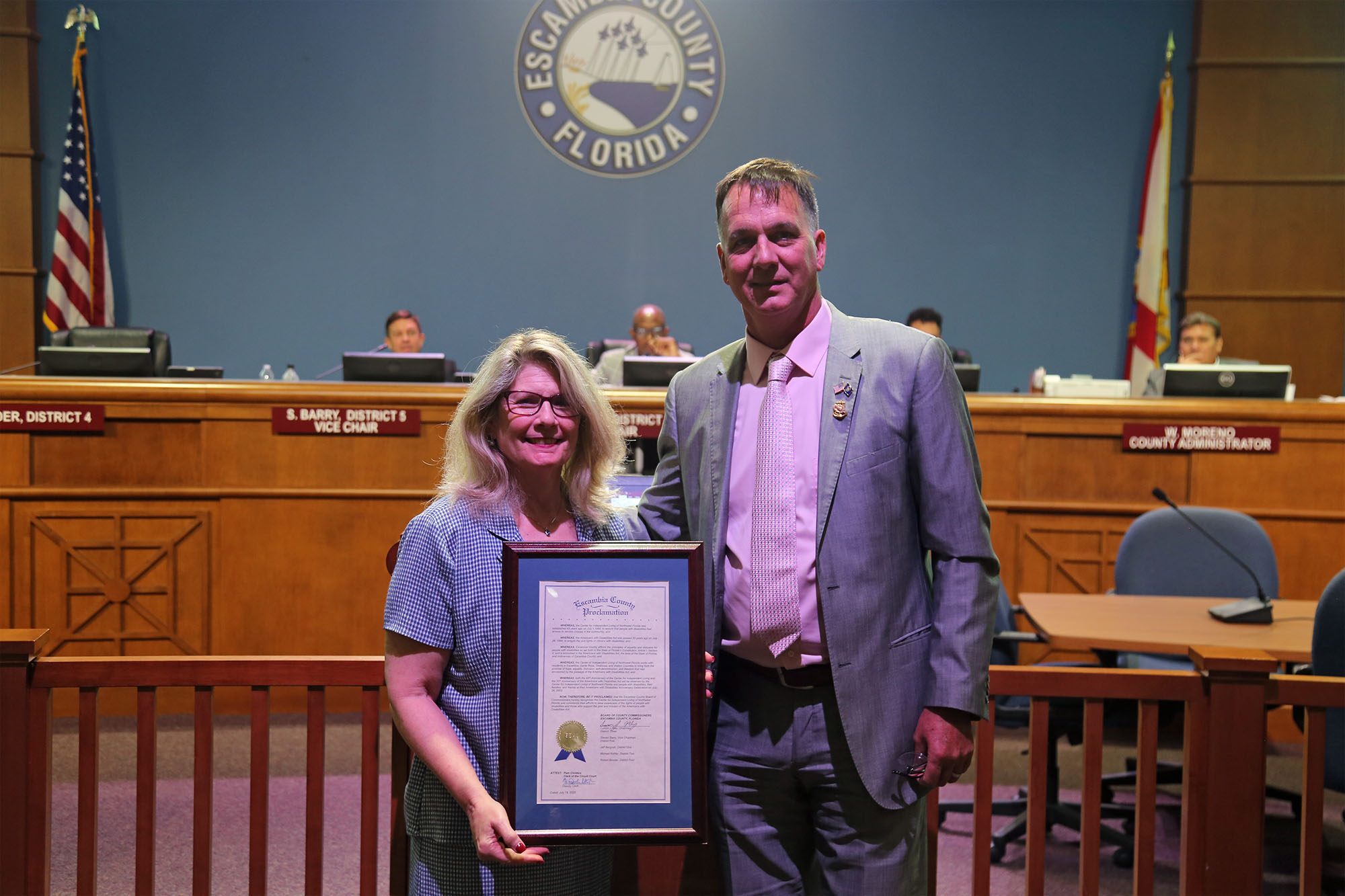 Commissioner Mike Kohler delivers a proclamation to Carolyn Grawi, CIL NWFL, during the July 18 BCC meeting.