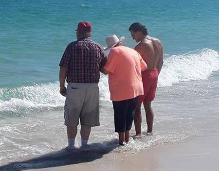 A lifeguard helps an elderly woman dip her toes in the Gulf of Mexico