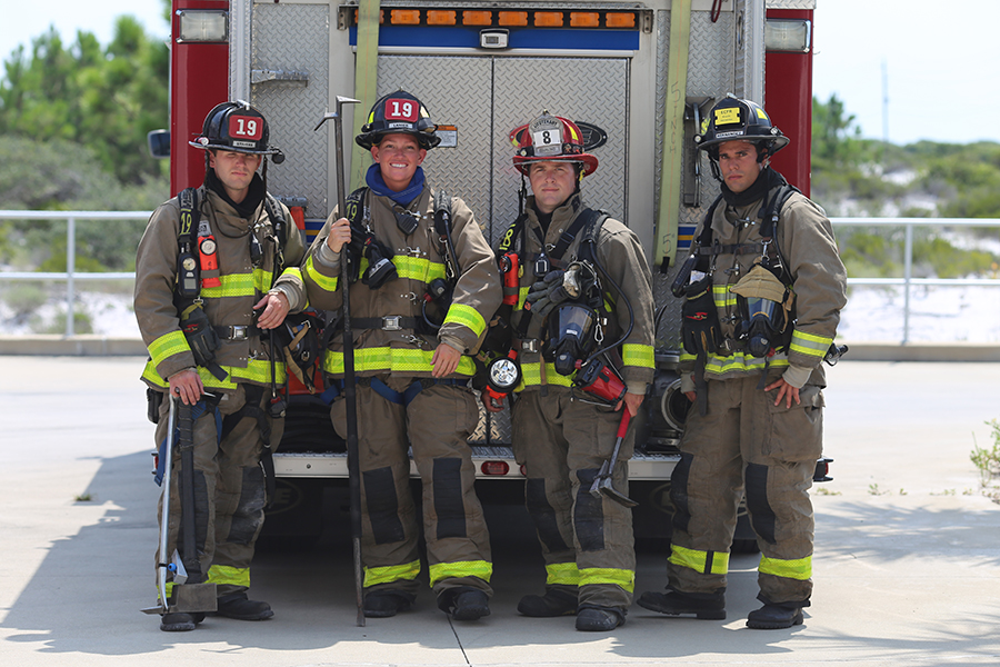 Firefighters stand in uniform by a fire truck