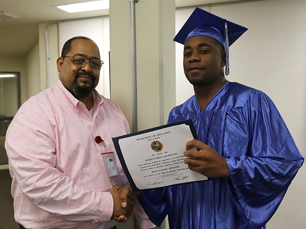 Charles Hall Darquavious Hamilton Instructor Charles Hall recognizes Darquavious Hamilton with his diploma at a GED graduation ceremony at the Escambia County Jail.