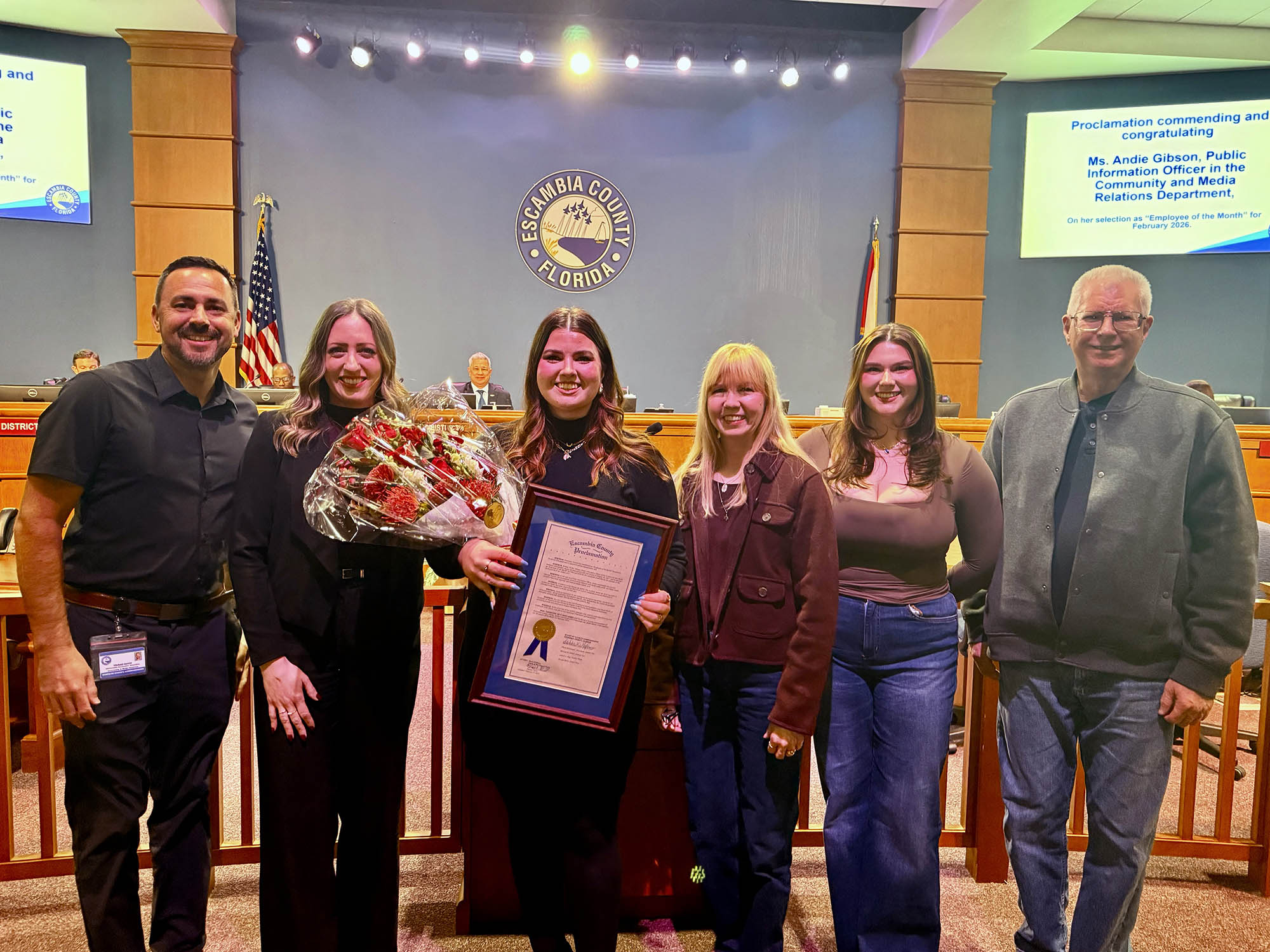 Woman accepting a proclamation with coworkers and family