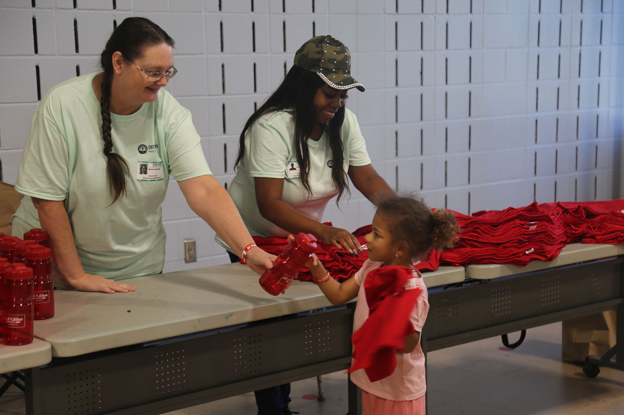 Day of Caring Woman handing a water bottle to a little girl