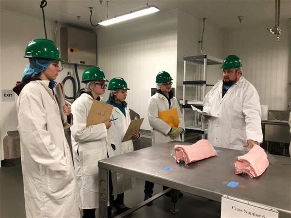 The Escambia County 4-H Meat Judging team reviews pork loins with Coach and 4-H Agent Brian Estevez