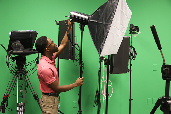 Youth employee James Hill works with lights in the studio of the Escambia County Board of County Commissioner chambers on Palafox Street.