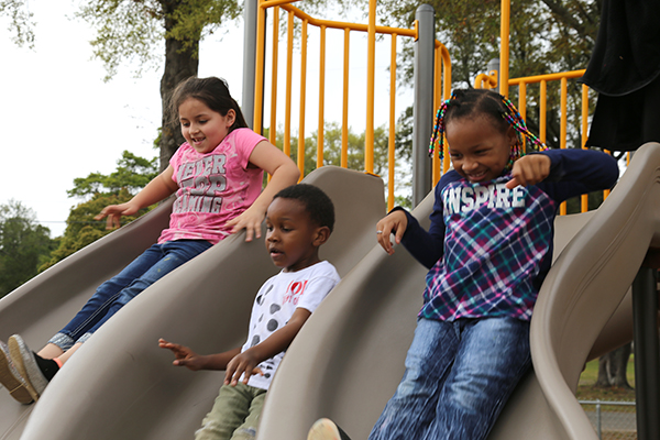 Children go down the slide at the recently-added playground outside the Brownsville Community Center.