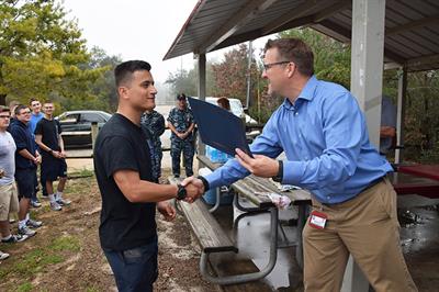 District 2 Commissioner's Aide Jonathan Owens presents a certificate to a volunteer at Perdido Kids Park. 