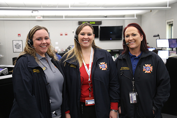 Three Emergency Communications dispatchers stand in the 911 call center at Escambia County Public Safety.